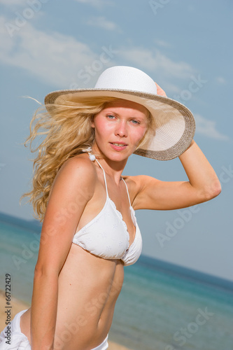 Young woman in white bikini holding sarong on the beach © Netfalls