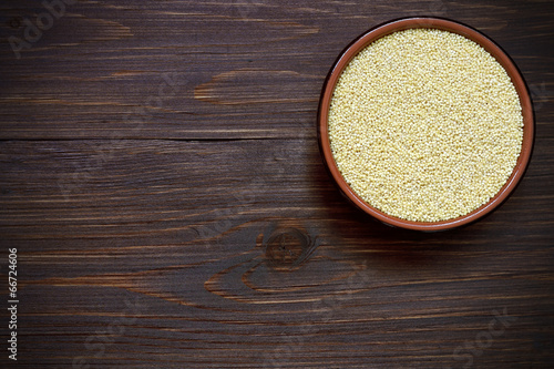 Organic uncooked millet in a bowl on a wooden table