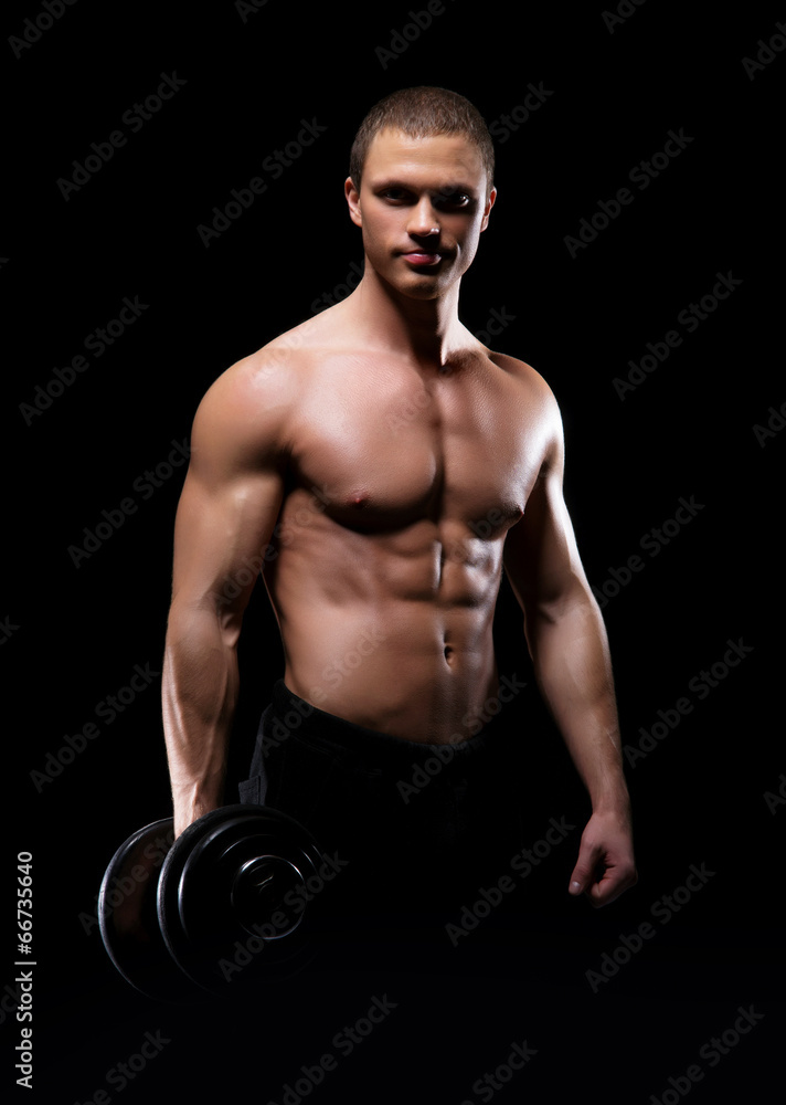 Strong, fit and sporty bodybuilder man with a dumbbell over blac