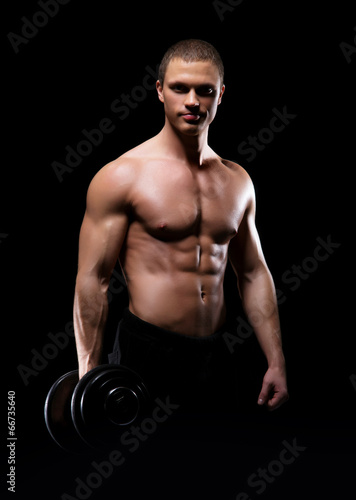 Strong, fit and sporty bodybuilder man with a dumbbell over blac © Acronym
