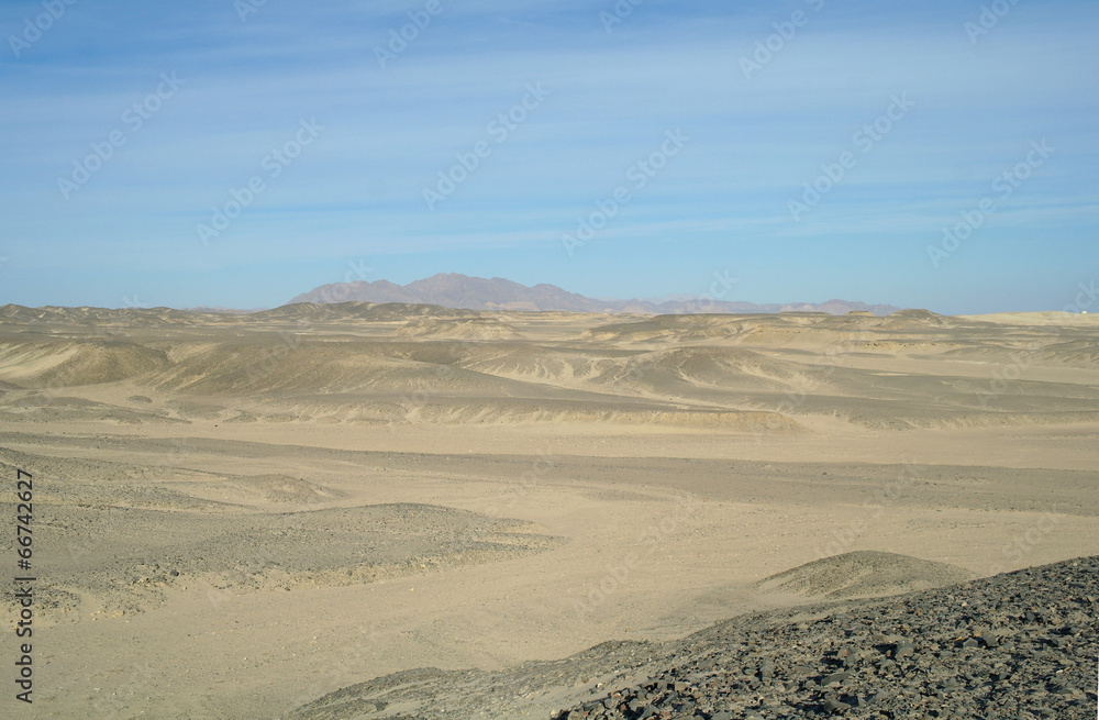 Egyptian desert covered by black stones and blue sky. Egyptian desert covered by black stones and blue sky.