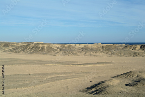 Egyptian desert covered by black stones and blue sky.