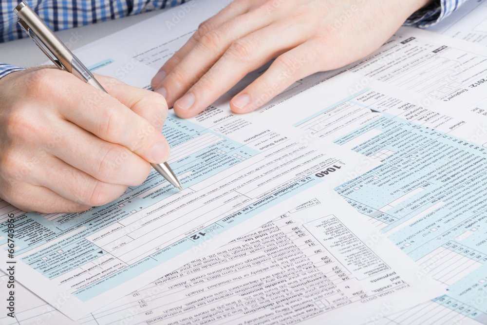 US 1040 Tax Form - male filling out tax form US 1040 Tax Form - male filling out tax form