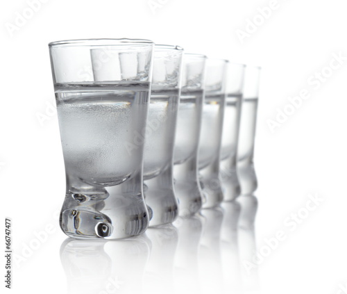 Many glasses of vodka isolated on white background