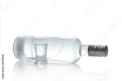 Bottle and glass of vodka lying isolated on white background