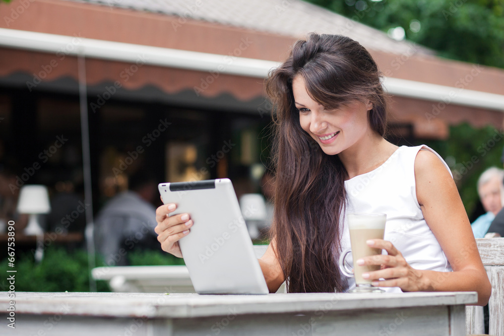 Young beautiful woman on a coffee break. Using tablet computer.