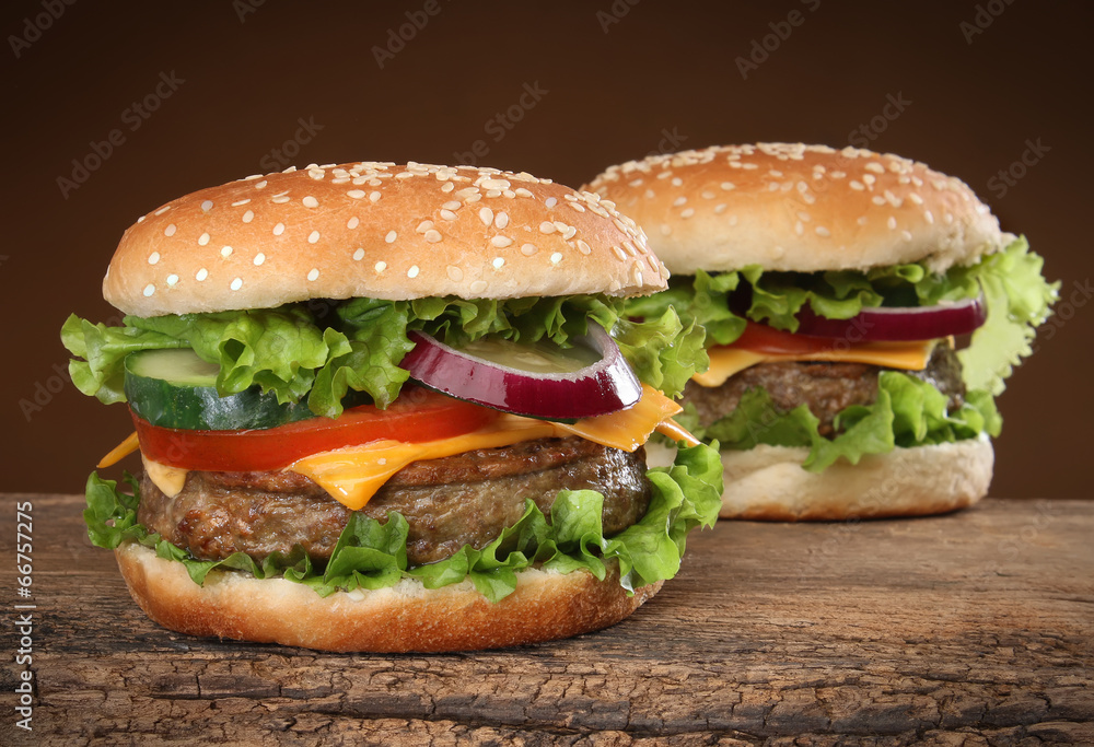 Two delicious hamburgers on wood background. Two delicious hamburgers on wood background.