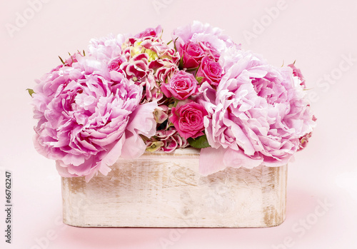 Pink peonies and roses in wooden box.