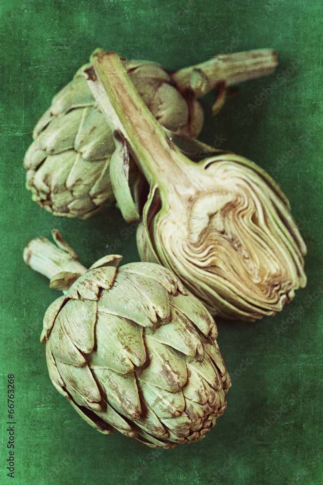 Fototapeta premium close up of a green fresh artichoke on a green background.