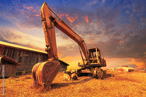 Old excavator standing with sunset background