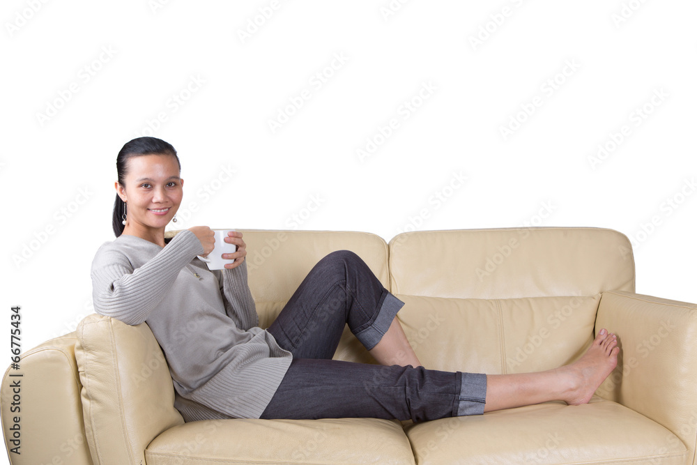Female Asian Malay relaxing on a sofa with a hot drink Female Asian Malay relaxing on a sofa with a hot drink