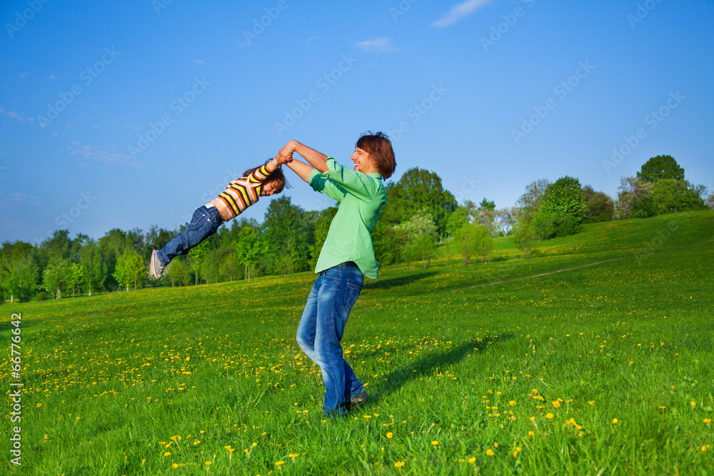 Father holds kid in the air while swirling him Father holds kid in the air while swirling him