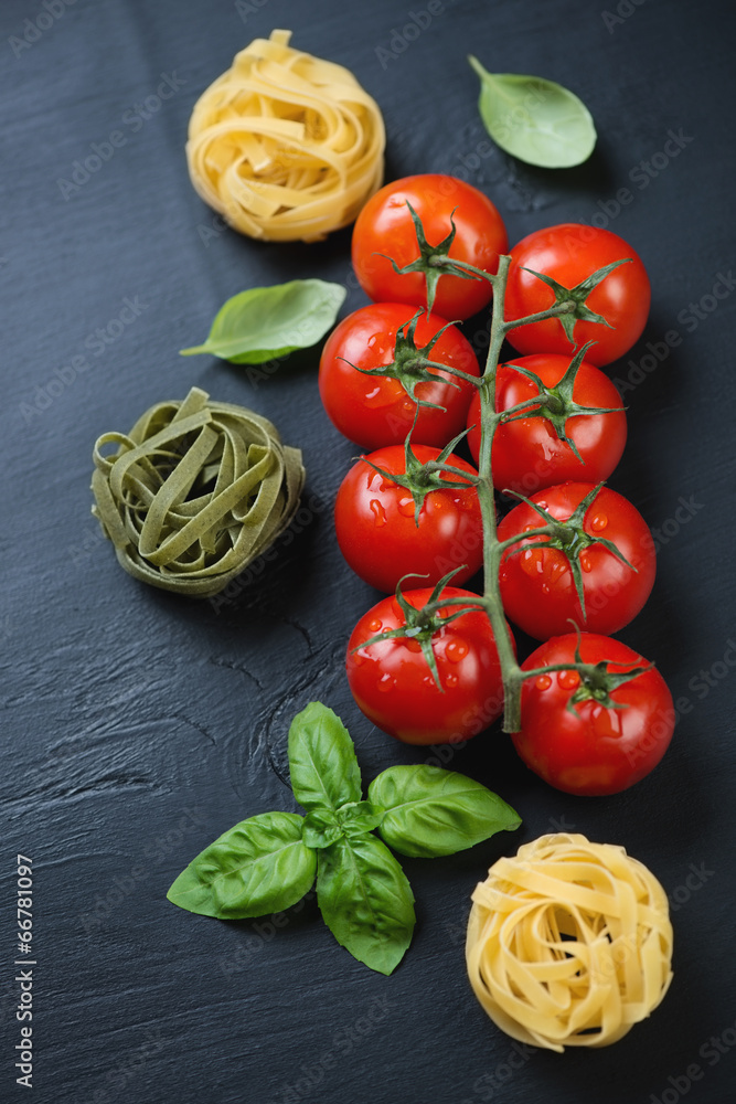 Above view of red tomatoes, green basil and pasta, vertical shot Above view of red tomatoes, green basil and pasta, vertical shot