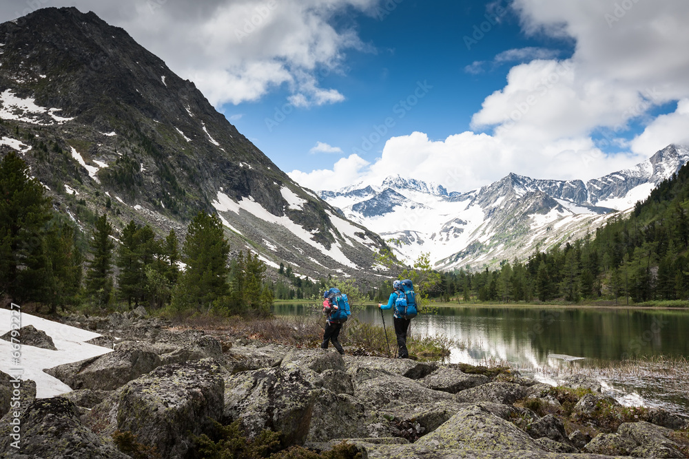 Hikers are walking by mountain lake in Altai mountains, Russia