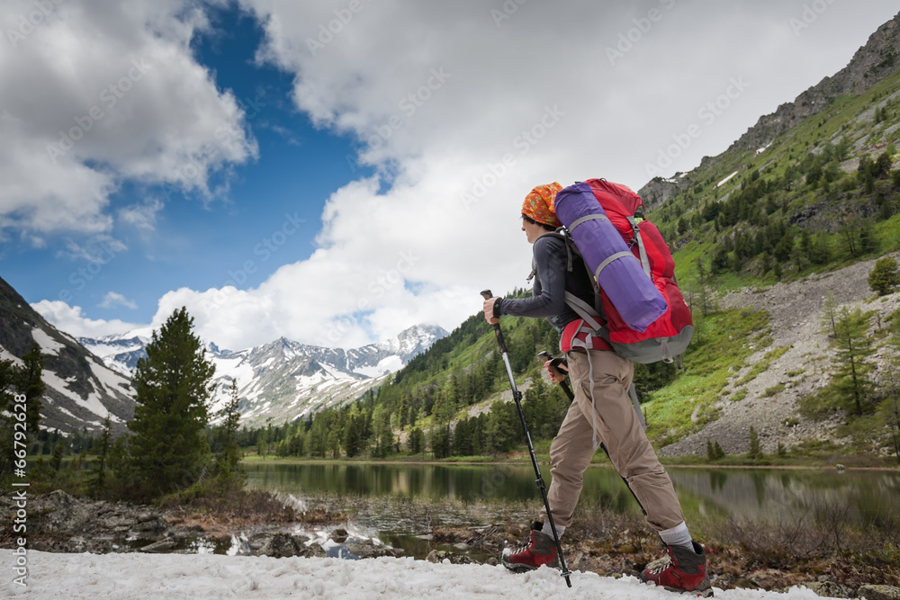 Hiker is walking by mountain lake in Altai mountains, Russia
