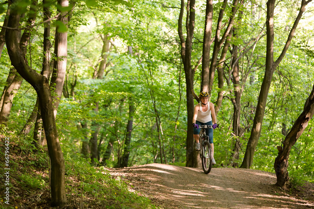 Woman is cycling in spring forest Woman is cycling in spring forest
