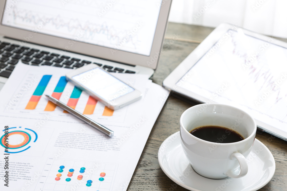 Laptop, tablet , smartphone and coffee cup with financial docume Laptop, tablet , smartphone and coffee cup with financial docume