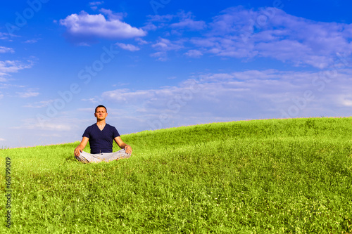 Handsome man meditating on the field. © Justinb