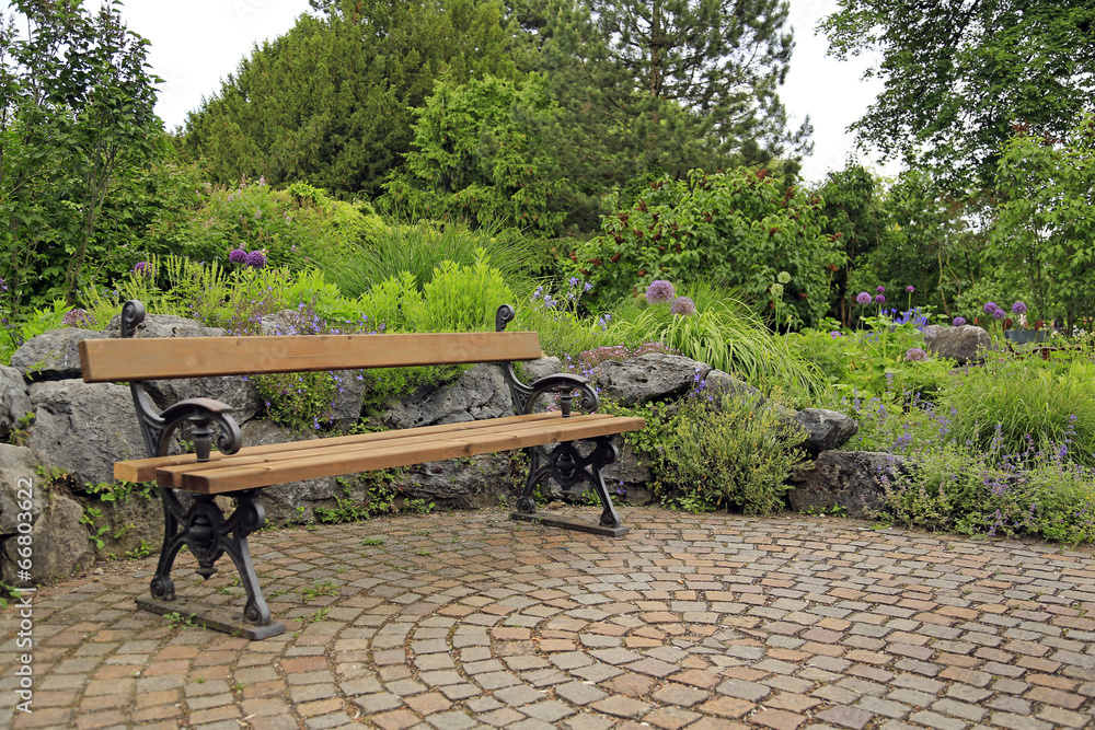 Ruheplatz im Garten: Bank auf einer mit Natursteinen gepflasterten Terrasse