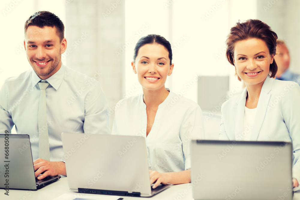 group of people working with laptops in office group of people working with laptops in office