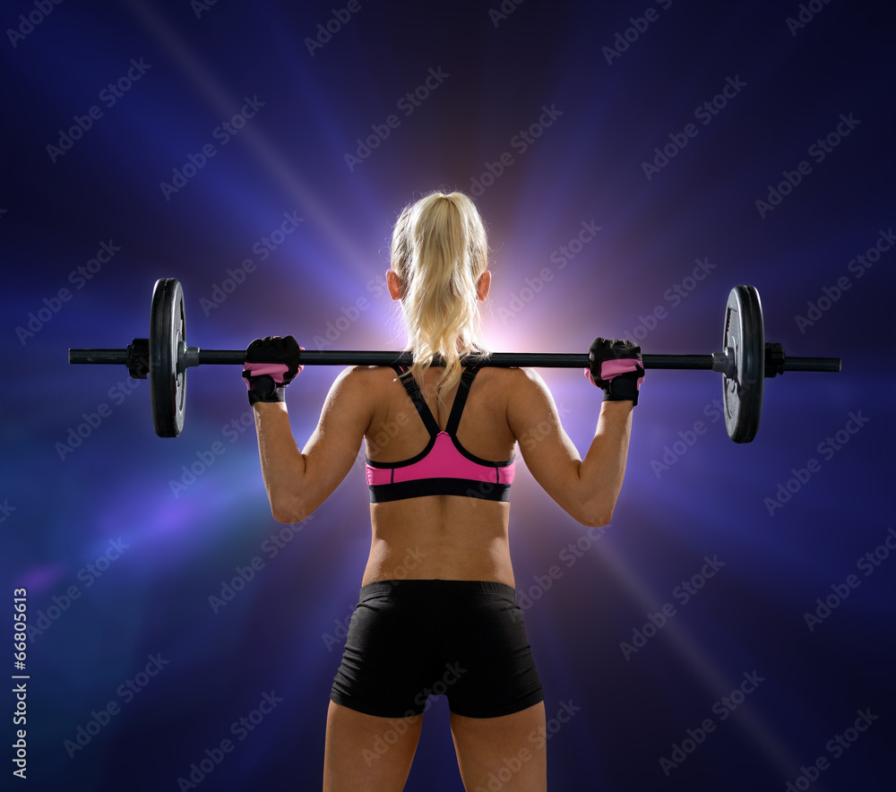 Obraz premium sporty woman exercising with barbell from back