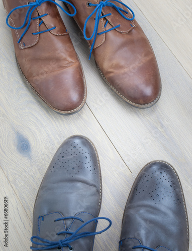 two pairs of shoes toe to toe on a wooden floor