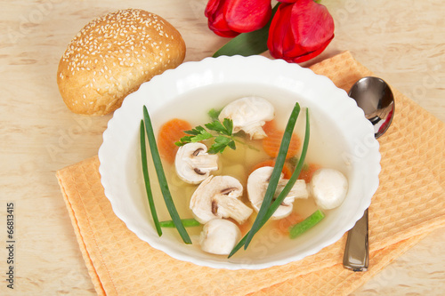 Plate with soup, spoon, bread and red tulips photo