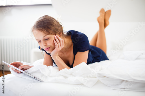 Elegant, smart, young woman using her tablet computer in bed