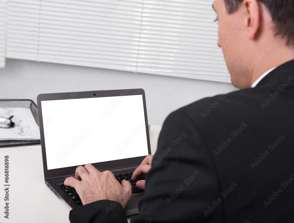 Rear view of businessman busy using laptop at office desk Rear view of businessman busy using laptop at office desk