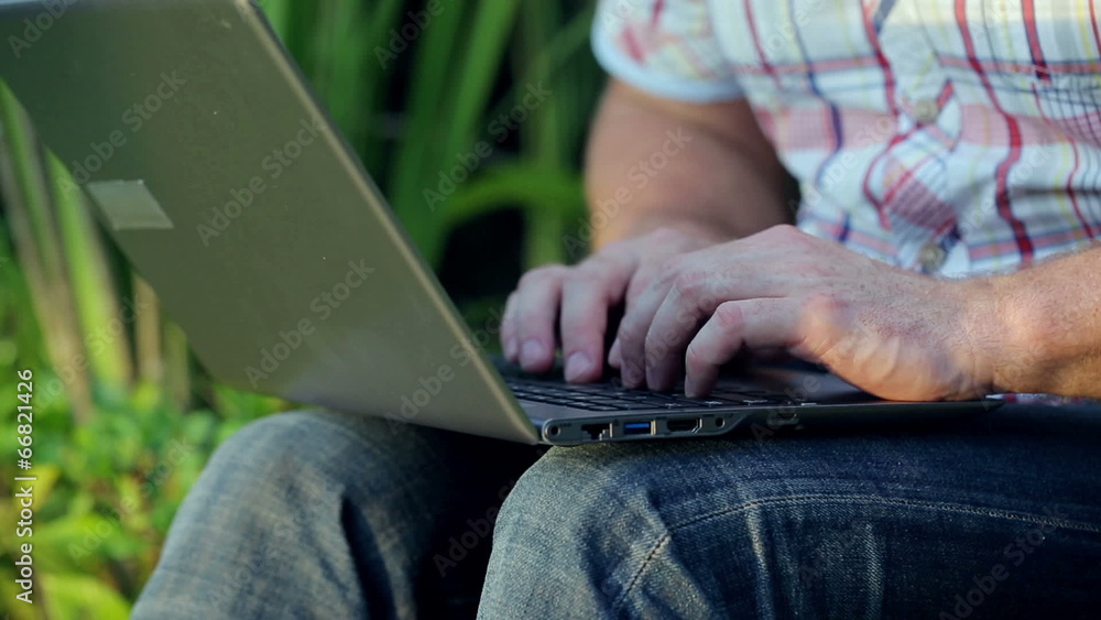 Man sitting in the garden and working on laptop Man sitting in the garden and working on laptop