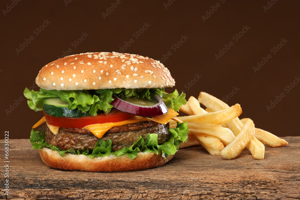 Tasty hamburger and french frites on wood background. Tasty hamburger and french frites on wood background.