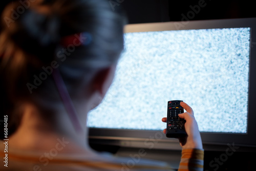 Fotografía Woman with remote control in front of TV set