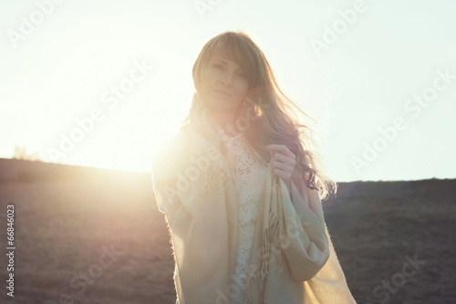 Young woman walking on beach under sunset light, outdoors