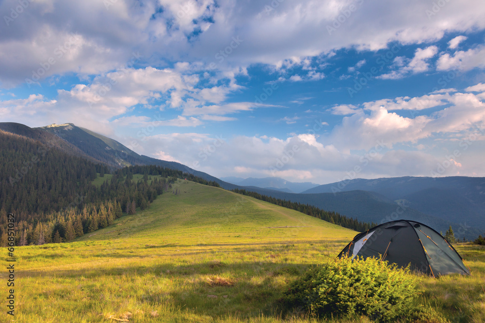 Camping tent in the mountains. Summer, blue sky, clouds and high