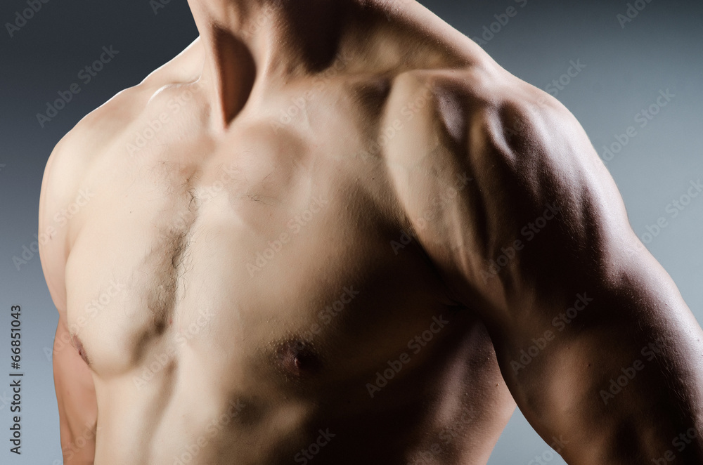 Fototapeta premium Muscular man posing in dark studio