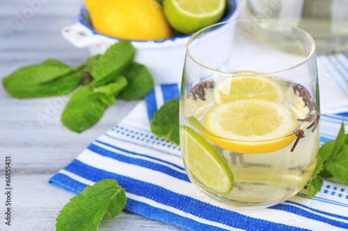 Fresh summer drink with lime and cloves in glass and jug,