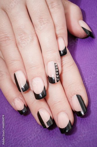 Female hands with black manicure on the violet background