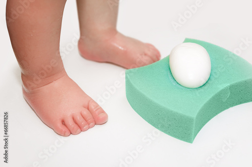 Baby feet, sponge and soap in bathtub