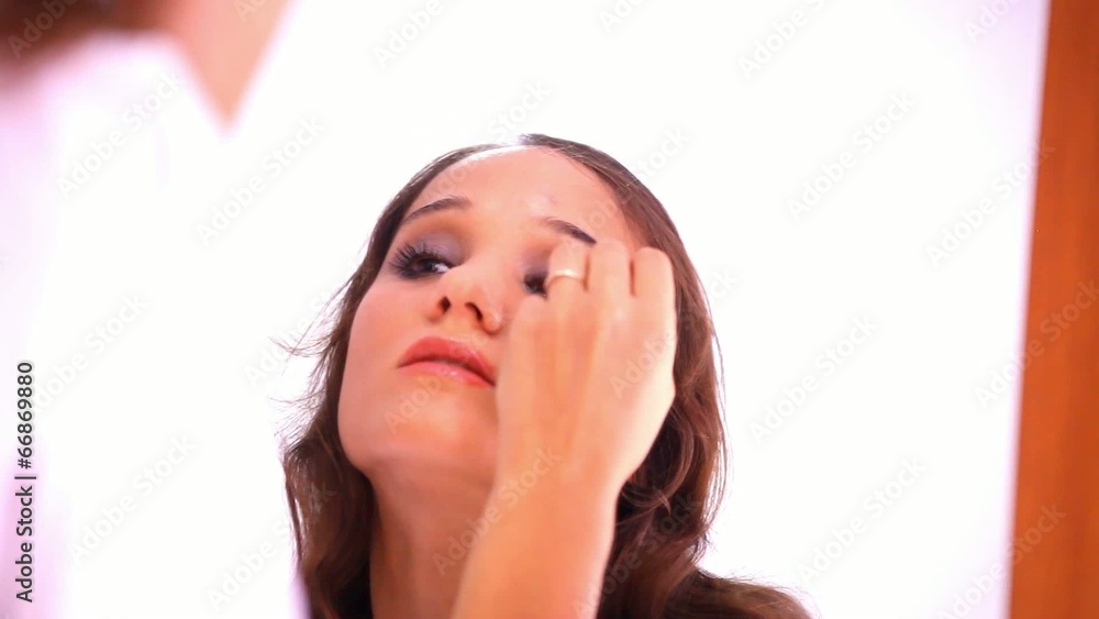 Beautiful young girl paints the eyelids and eyelashes at mirror. Beautiful young girl paints the eyelids and eyelashes at mirror.