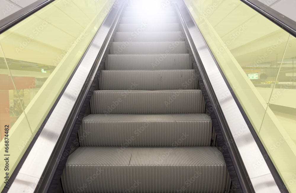 Empty escalator or moving stair. Also called stairway or staircase. Modern architecture design with step, glass for lift people up floor building i.e. shopping mall, airport, metro and subway station. Empty escalator or moving stair. Also called stairway or staircase. Modern architecture design with step, glass for lift people up floor building i.e. shopping mall, airport, metro and subway station.