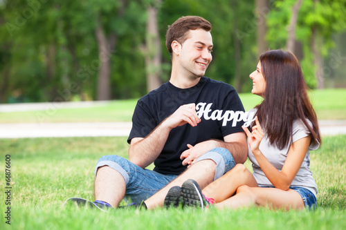 Teen couple with word Happy in the park.