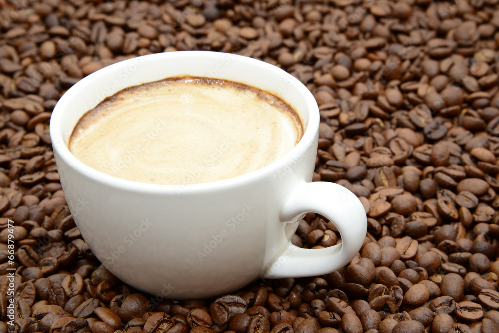 Obraz premium cup of coffee with cream on a coffee beans background