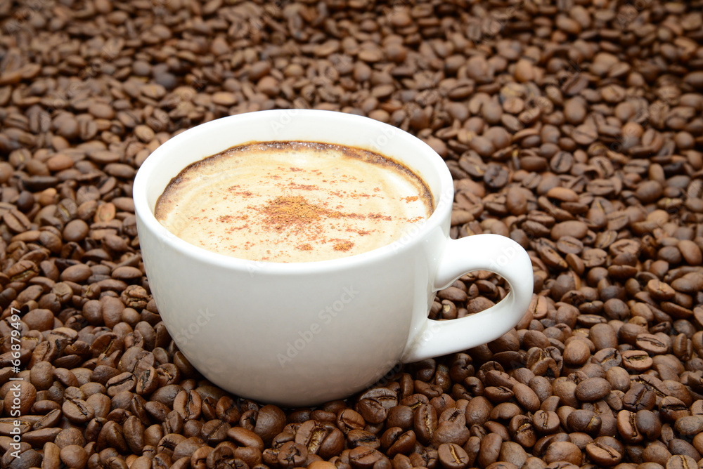 cup of coffee with cinnamon on a coffee beans background cup of coffee with cinnamon on a coffee beans background
