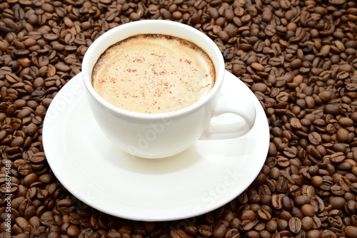 cup of coffee with cinnamon on a coffee beans background