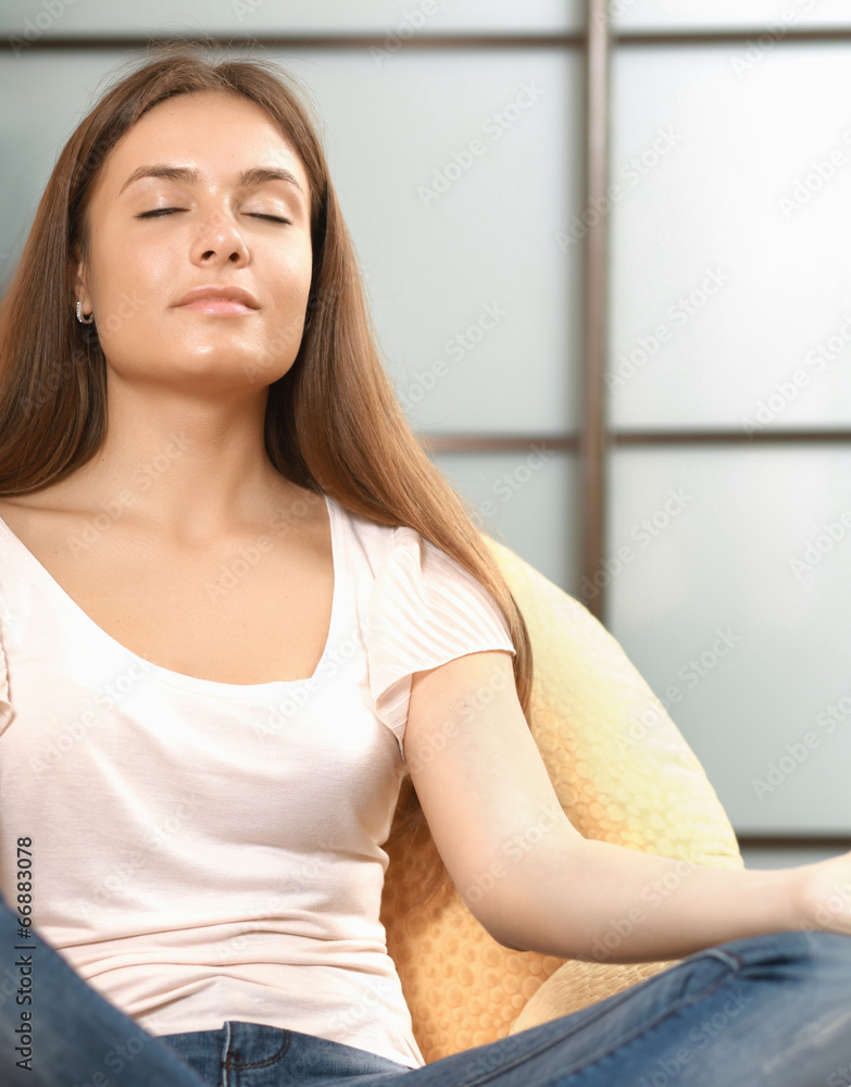 Young woman sitting on a sofa in the lotus position Young woman sitting on a sofa in the lotus position
