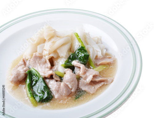 Noodle with pork and kale topping served in white bowl