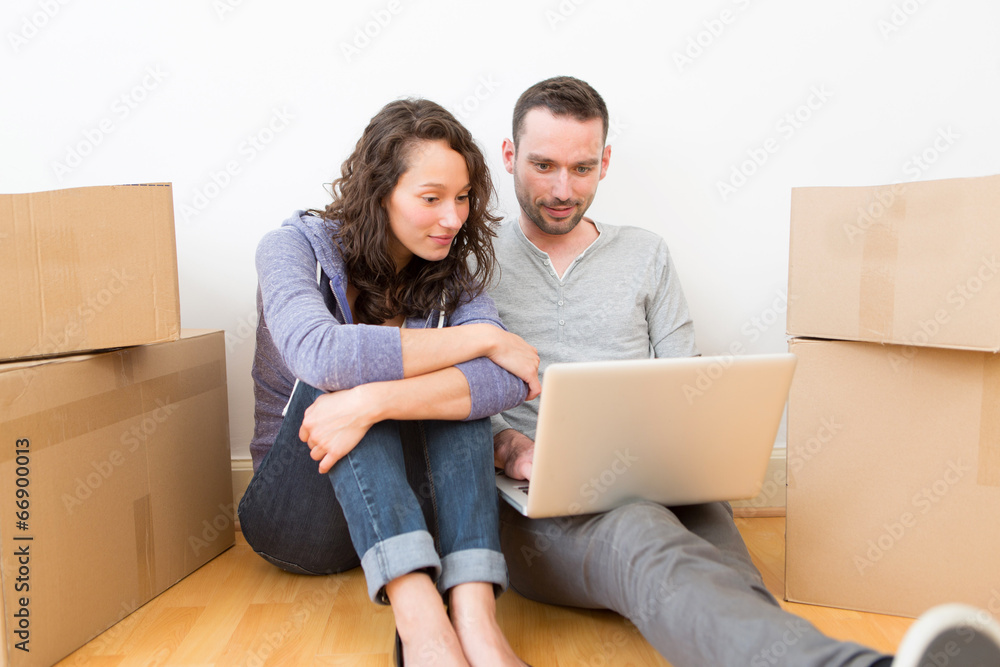 Young couple using laptop while moving in new flat Young couple using laptop while moving in new flat