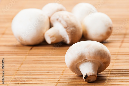 Bunch of champignon mushrooms on bamboo plate.