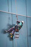 worker cleaning windows service on high rise building