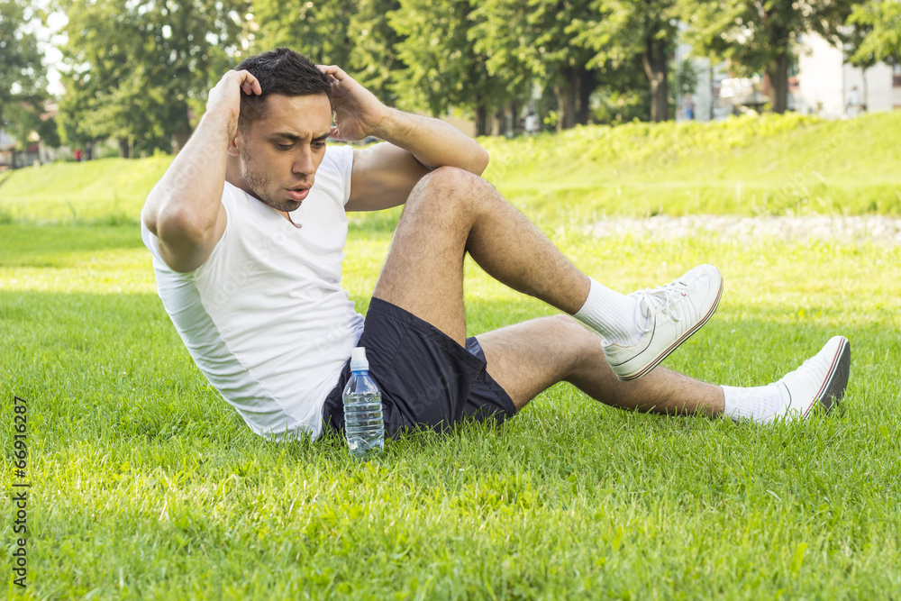 Fitness man exercising sit up outside in grass in summer Fitness man exercising sit up outside in grass in summer